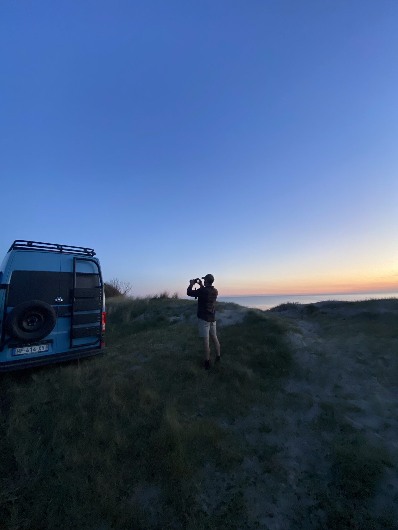 Silhouette avec jumelles au crépuscule sur les dunes